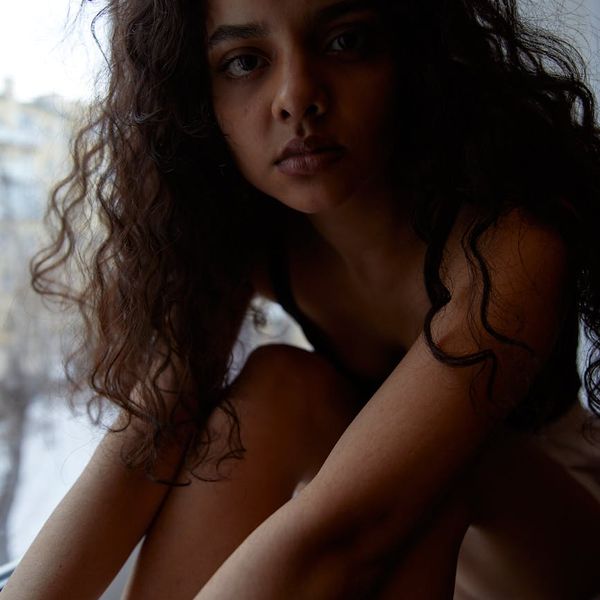 Person sitting peacefully by a window looking out with a calm expression.